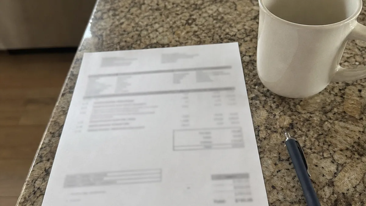 A smartphone showing a text beside a printed quote and pen on a kitchen counter
